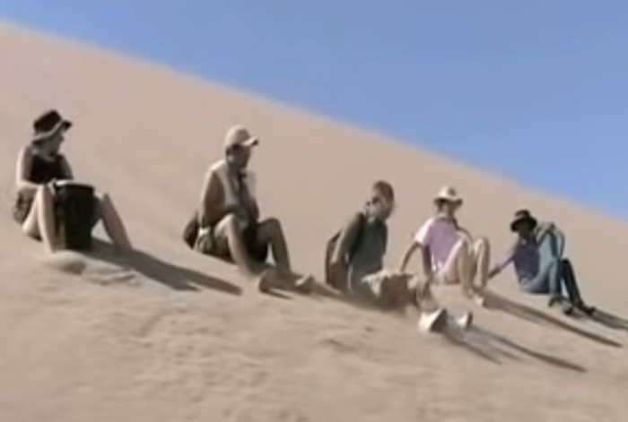 pessoas deslizando duna abaixo